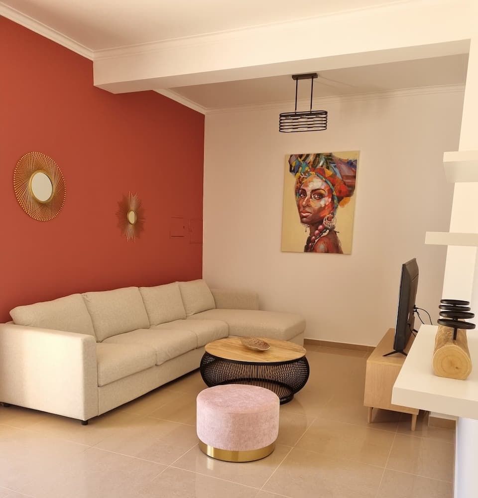 The living room includes a corner sofa, television, and a corner office space.
