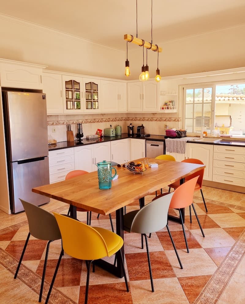 The fully equipped kitchen includes a refrigerator, induction cooker, oven, microwave, dishwasher, Nespresso coffee machine, kettle, juicer, and toaster. A large table provides plenty of seating for 8.