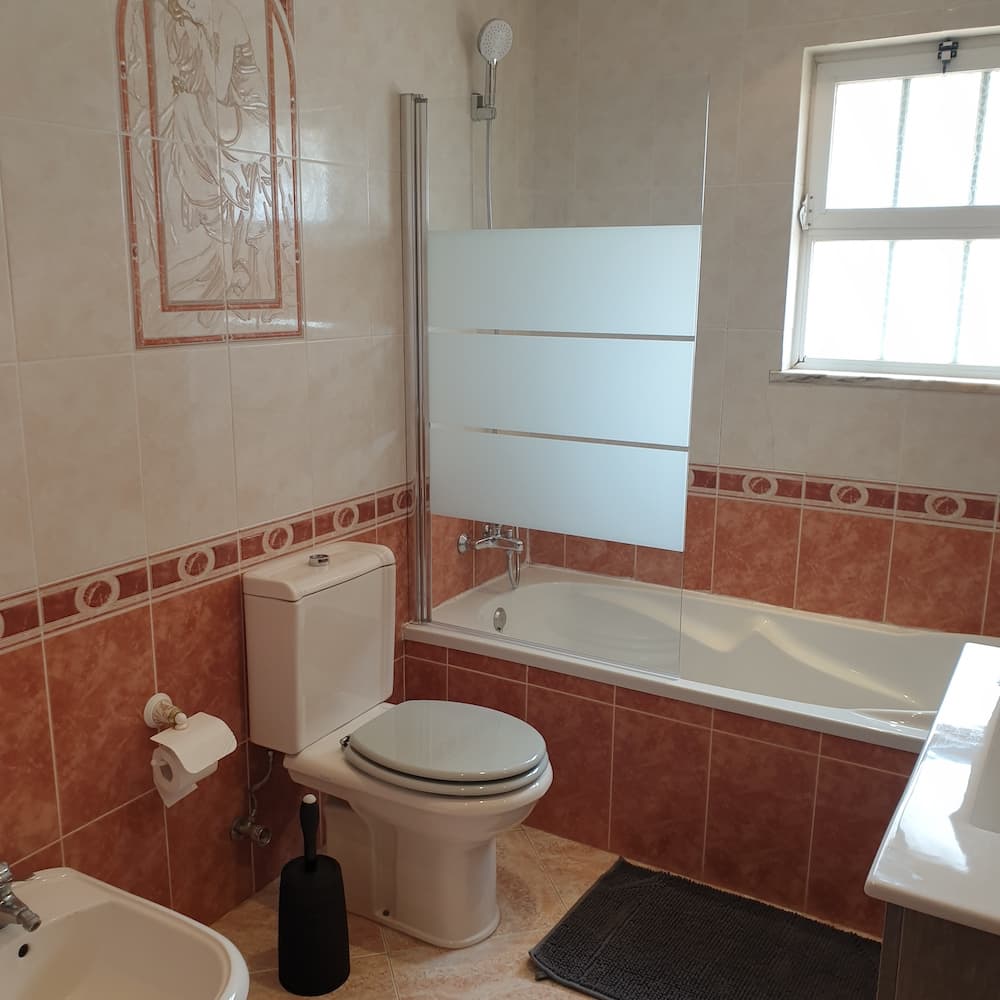 This bathroom includes a bidet and a deep soaking bathtub with showerhead.